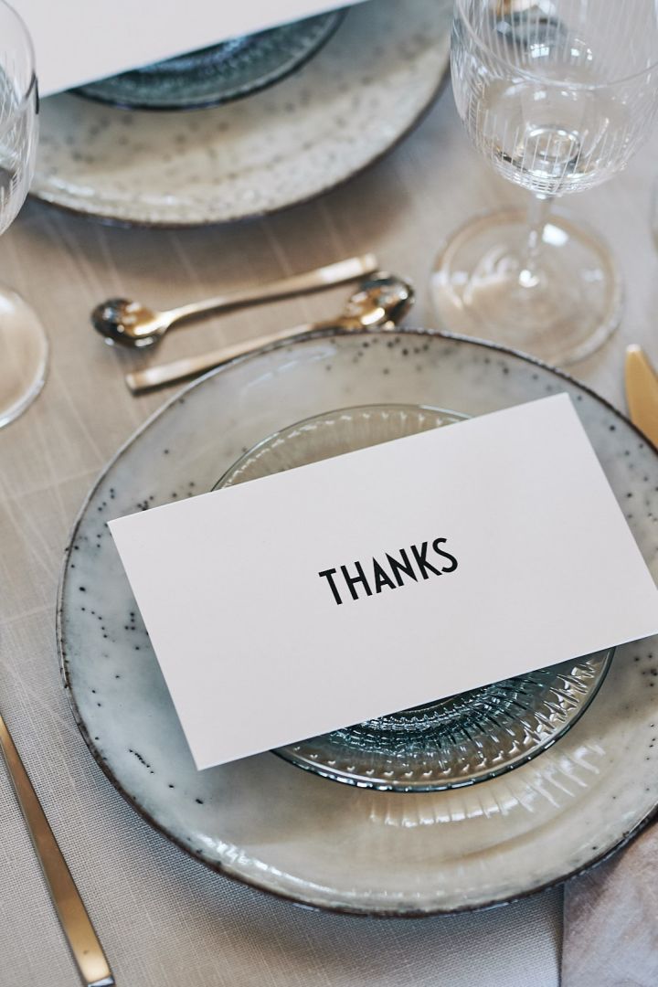 Es wird für viele mit Nordic Sand Teller, Glasteller von Kähler und einer Dankeskarte dekoriert. Das silberne Fuga-Besteck von Gense vervollständigt das Tischgedeck. 