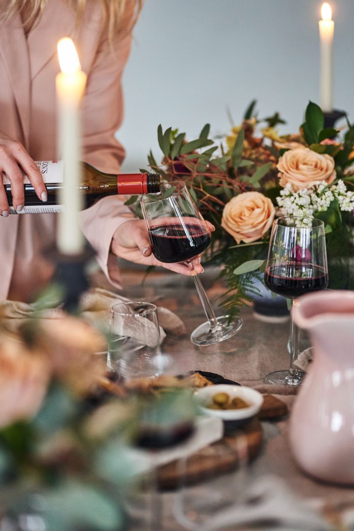 Frühlingshaft gedeckter Tisch in rosa Pastelltönen mit dem Rotweinglas Essence von Iittala im Mittelpunkt. 