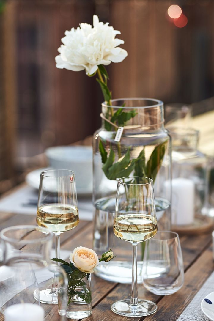 Eine moderne Tischdekoration mit Essence-Weißweingläsern von Iittala, deren schlichtes Design von Kerzenleuchtern und Glasvasen aufgegriffen wird. 