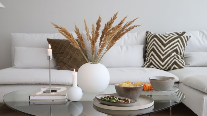 Runde Vasen von Cooee Design mit Pampasgras und Kerzenständer in Weiß auf einem Couchtisch.