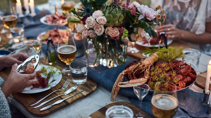 Krebsfest - gedeckter Tisch mit Meeresfrüchteplatte und Blumenstrauß.