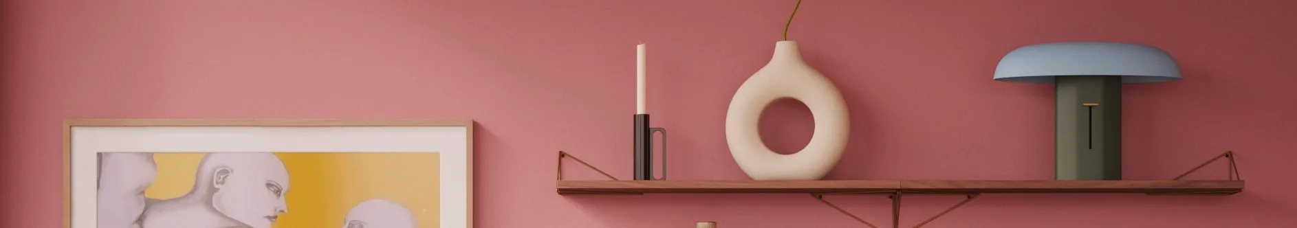 Rosa Wand, Holzregal: weiße Kerze, cremefarbene Donut-Vase mit grünem Stiel, blau-grüne Lampe. Gerahmtes Kunstwerk links.
