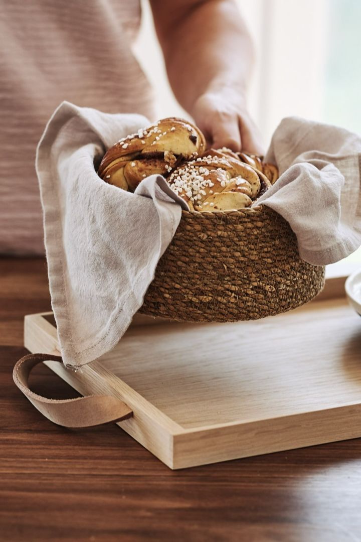 Der Kaffee wird in der Küche zubereitet, mit Brot in einem Brotkorb und Kaffeetassen auf einem Holztablett. 