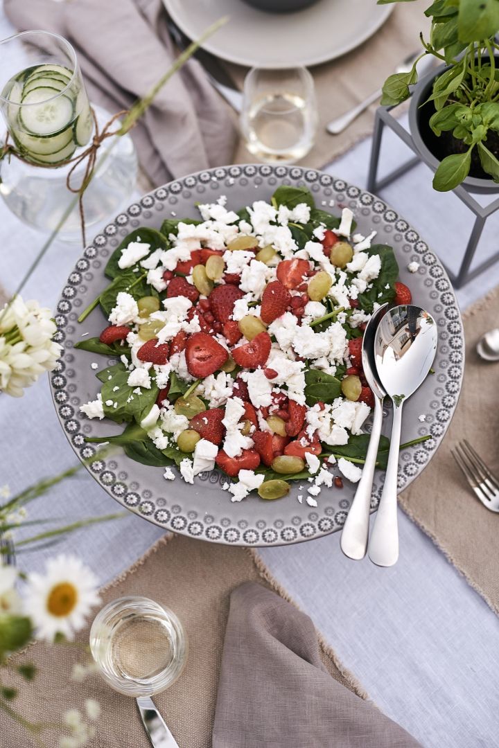 Ein herrlicher Sommersalat mit Erdbeeren und Fetakäse, serviert auf einer grauen Kuchenplatte, ist der Hauptgang des sommerlichen Mittagessens. 