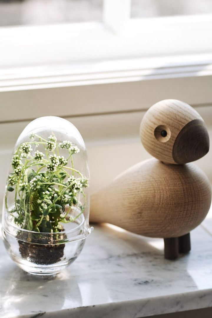 Grow Mini-Gewächshaus von Design House Stockholm und ein Kay Bojesen-Vogel zieren die Fensterbank im skandinavisch gestalteten Wohnzimmer. 