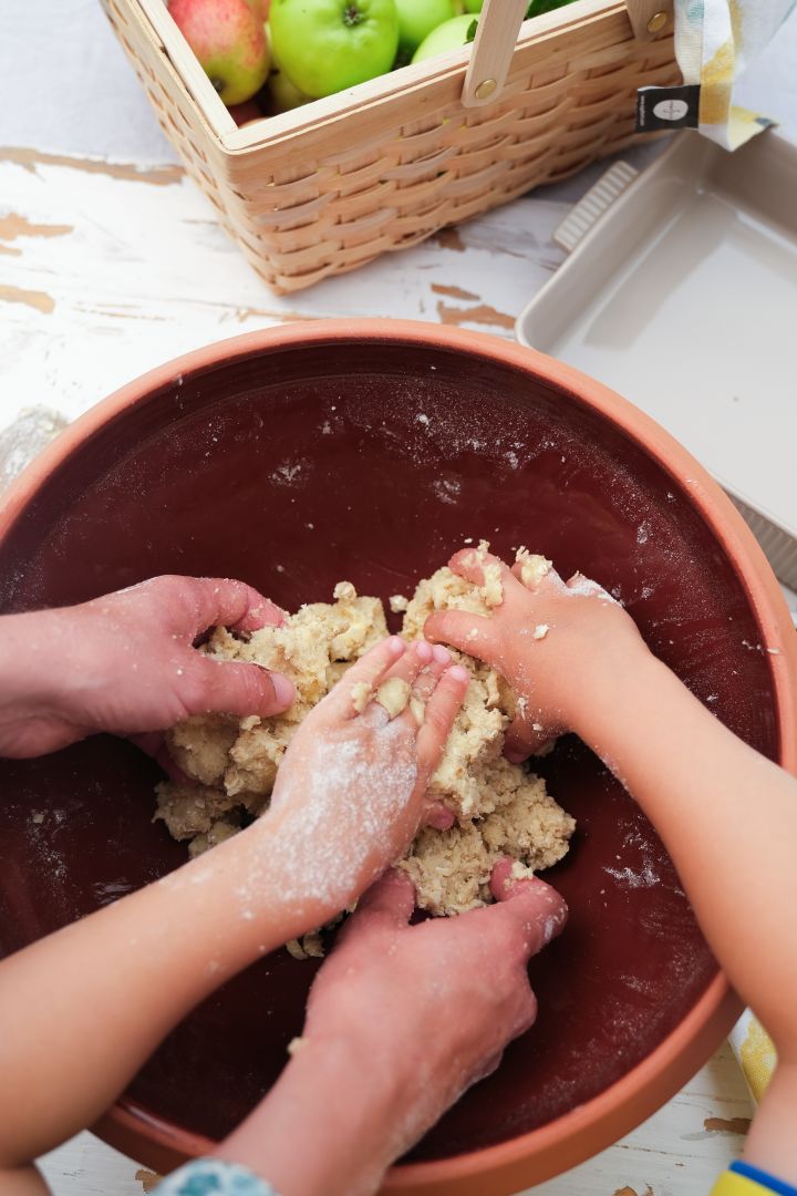 Das Bild zeigt Hände beim Kneten und Mischen von Streuselteig für einen Apfelkuchen, hier in der Knabstrup Teigschüssel.