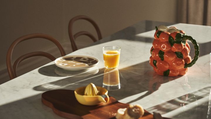 Hier sehen Sie einen gedeckten Tisch mit Marimekko-Porzellan, Saft und Karaffe von BYON im Design von Mandarinen. 