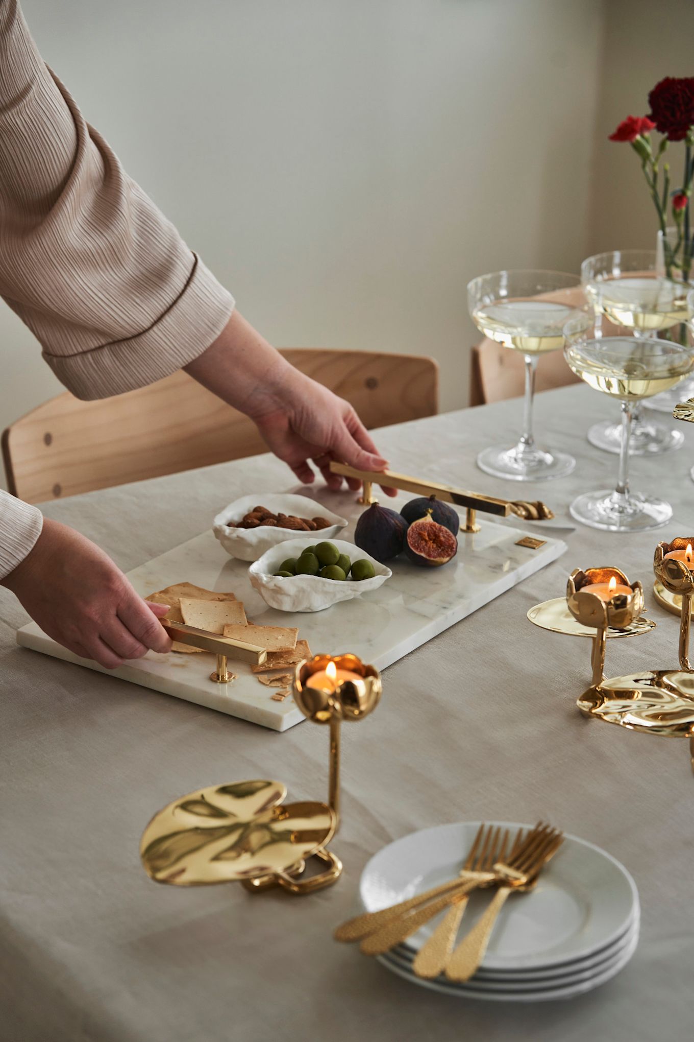 Laden Sie Ihre Freundinnen zum Nachmittagstee am Galentine's Day ein. Hier sehen Sie ein Marmortablett von Hilke Collection und goldene Kerzenhalter in Form von Seerosen.