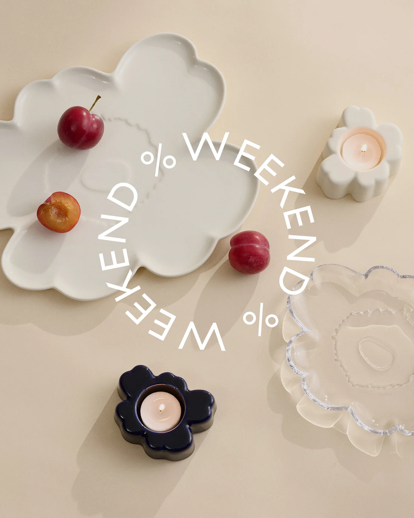 Dekorative Teller und Kerzenhalter in Weiß, Blau und Klarglas mit Pflaumen auf beigem Hintergrund. Weißer Text 'Weekend %'.