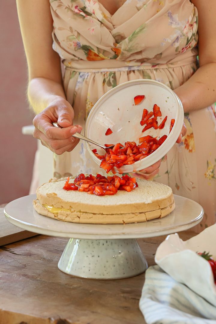 Die schwedische Back-Influencerin Baka med Frida präsentiert Ihre einfachen Tortenrezepte zu Mittsommer. Zu diesen gehört auch eine schwedische Erdbeertorte, für welche die geschnittenen Erdbeeren auf dem Tortenboden verteilt werden.