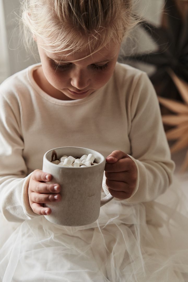 Hier sehen Sie ein Mädchen mit heißer Schokolade in einem Becher aus der Sandsbro-Kollektion von Scandi Living.