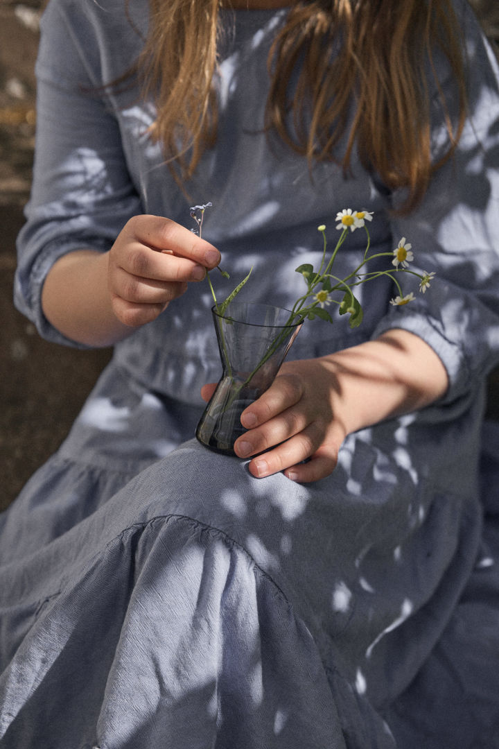 Eine Mittsommer-Tradition in Schweden besteht darin, Blumen zu pflücken. Hier sehen Sie ein Mädchen in blauem Kleid mit einer Midsummer-Vase mit Blumen auf dem Schoß.