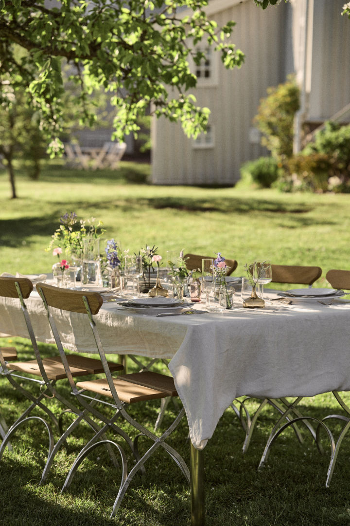 Hier sehen Sie einen fürs schwedische Mittsommerfest dekorierten Tisch im Garten.