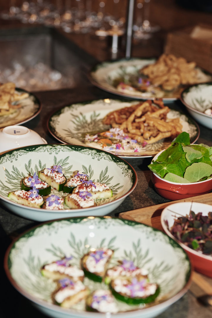 Hier sehen Sie den Ostindia Floris tiefen Teller mit einer professionellen Servierplatte. Teil einer grünen Tischdekorationsidee für ein Restaurant, das sich wie zu Hause fühlt. 