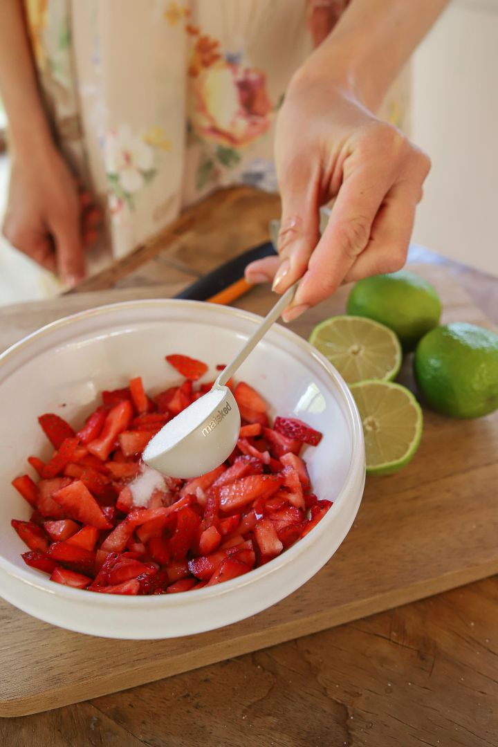 Ein einfaches Tortenrezept zu Mittsommer ist eine klassische schwedische Erdbeertorte. Zur Vorbereitung gibt Frida die frisch geschnittenen Erdbeeren in eine Schüssel, bestreut sie mit Zucker und gibt Limettensaft darüber.