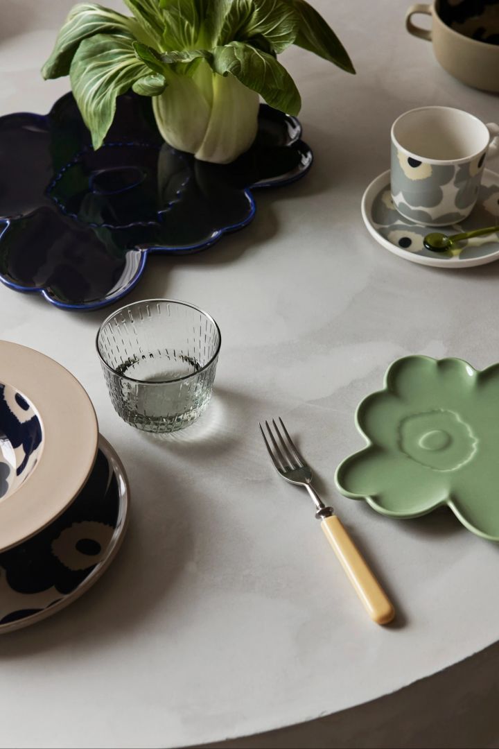 Set mit Unikko-Porzellan von Marimekko, darunter zwei blumenförmige Teller in Mintgrün und Dunkelblau.