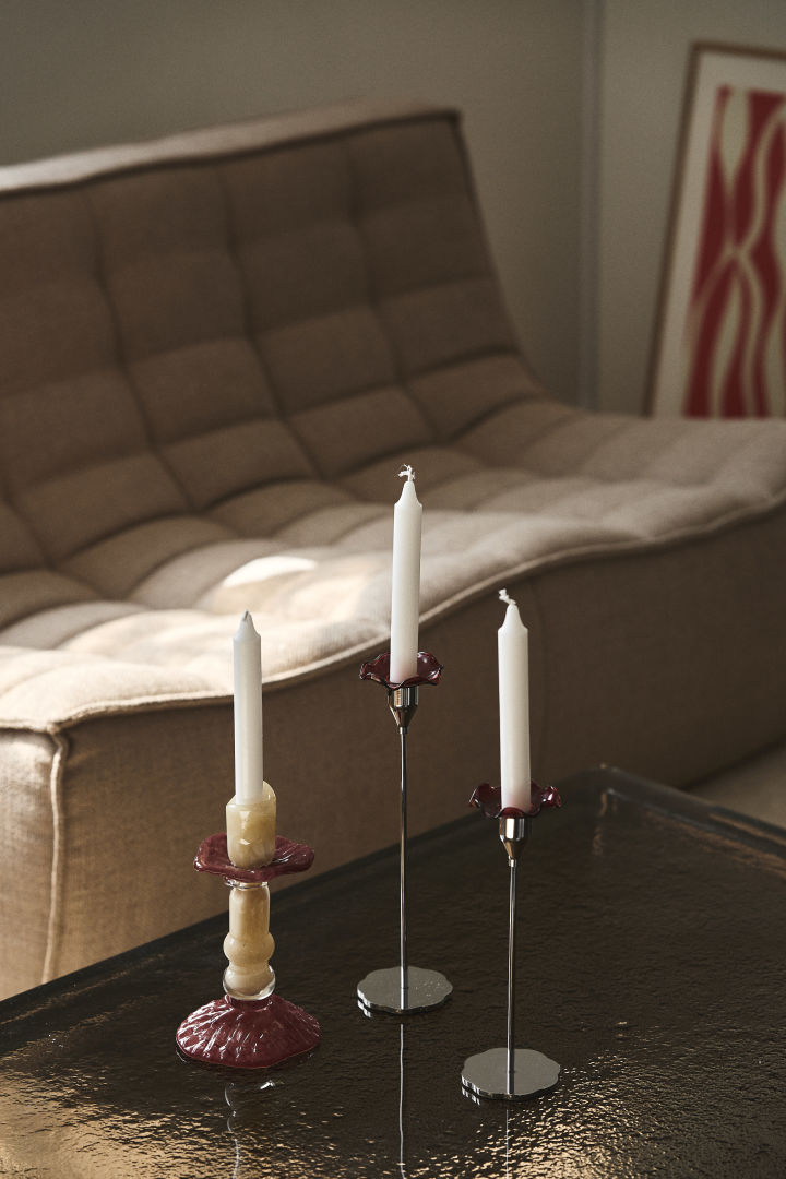 Der Kerzenständer Lara von Byon, hier auf einem Couchtisch mit Glasplatte, ist aus farbigem Glas in Beige und Burgunderrot gefertigt, das Design ist von römischen Säulen inspiriert.