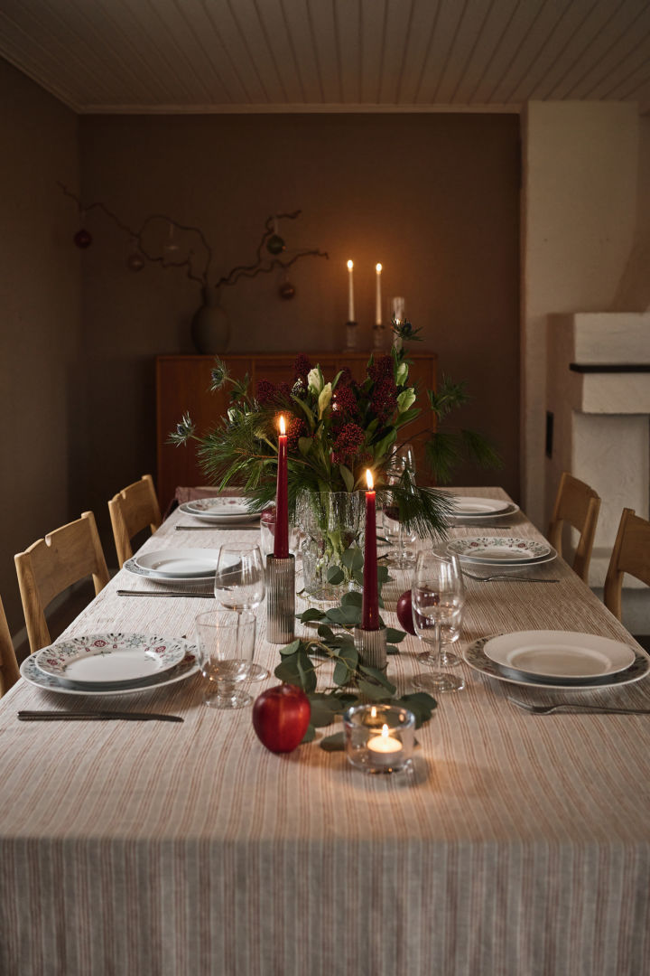 Ein stimmungsvoller weihnachtlicher Tisch mit roten Kerzen und bedrucktem Weihnachtsgeschirr. 