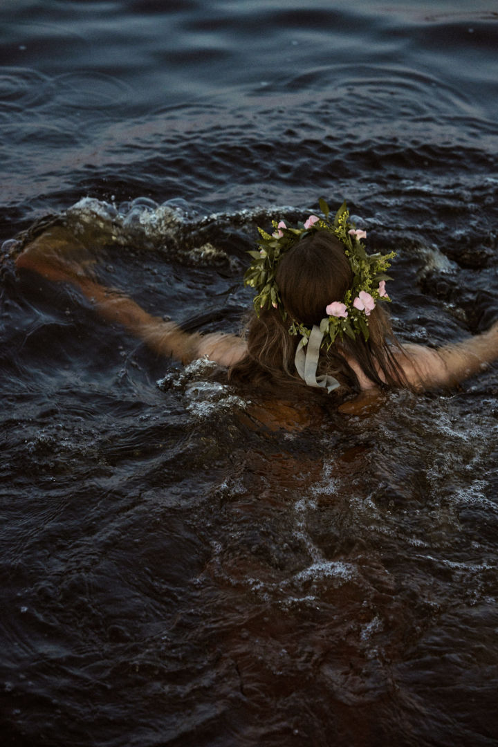 Ein Bad im nächstgelegenen See ist ein Muss während des Mittsommerfestes, hier sehen Sie eine Frau mit Mittsommerkranz schwimmen.