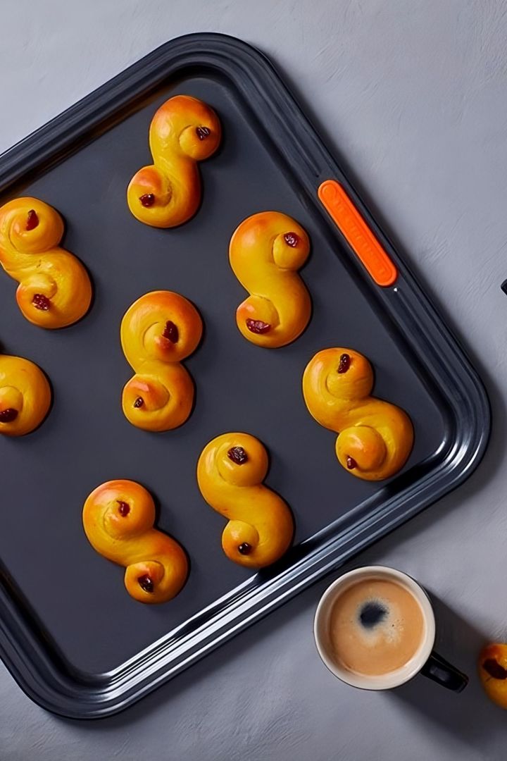 Lussekatter sind ein besonderes schwedisches Gebäck, das vorrangig zur Weihnachtszeit gegessen wird. Hier sehen Sie herrlich goldbraun gebackene Lussekatter auf einem Le Creuset Ofenblech.